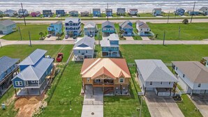 A coastal residential area with houses, a beach, and a clear sky. - Copper Top by Ryson Vacation Rentals (Galveston)