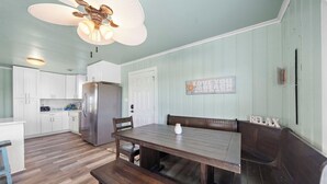 A kitchen with white cabinets, a wooden dining table, and a bench. - Colva Tides by Ryson Vacation Rentals (Galveston)