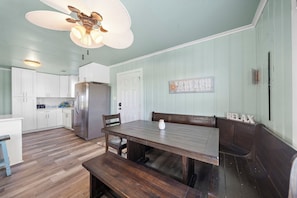 A kitchen with white cabinets, a wooden dining table, and a bench.