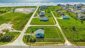 An aerial view of a coastal residential area with houses, roads, and a beach. - Colva Tides by Ryson Vacation Rentals (Galveston)