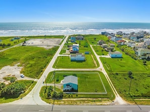 An aerial view of a coastal residential area with houses, roads, and a beach.