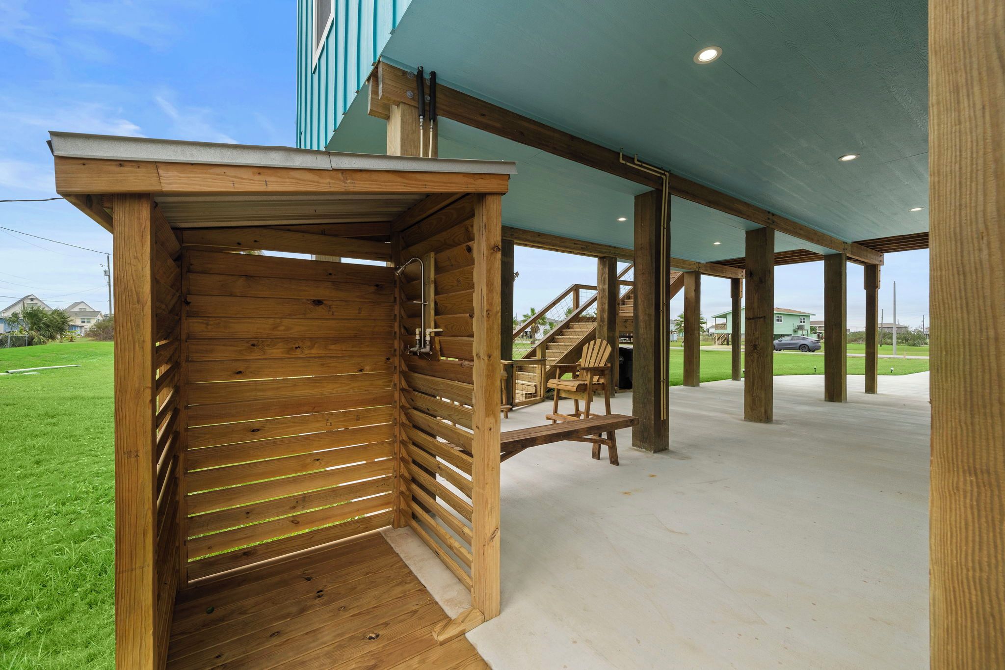 A covered outdoor area with wooden benches and a staircase leading to an upper level.