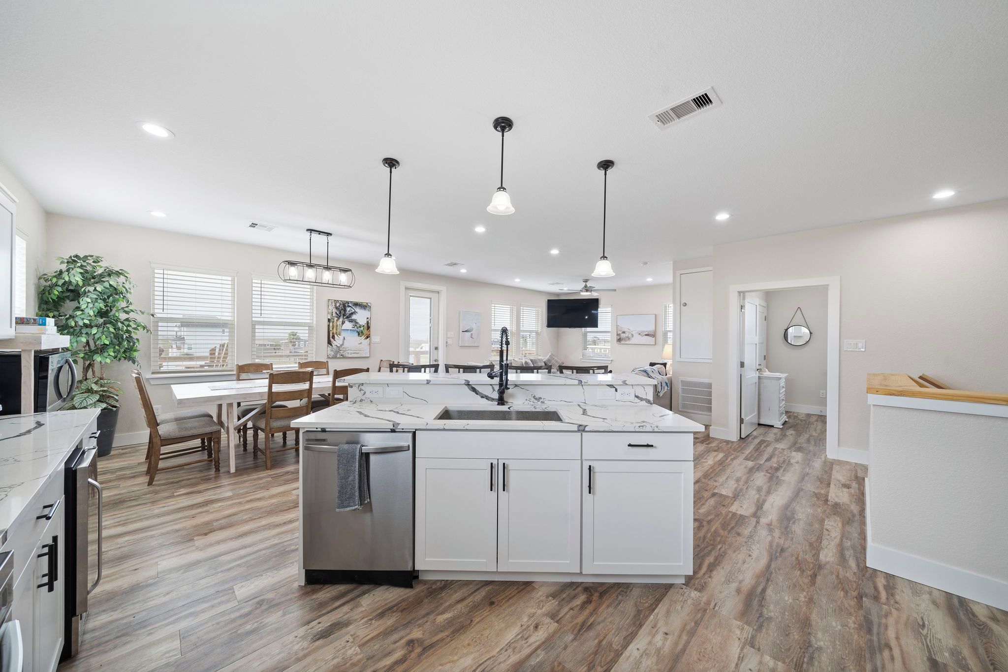 A modern kitchen with white cabinets, a marble island, and pendant lighting.