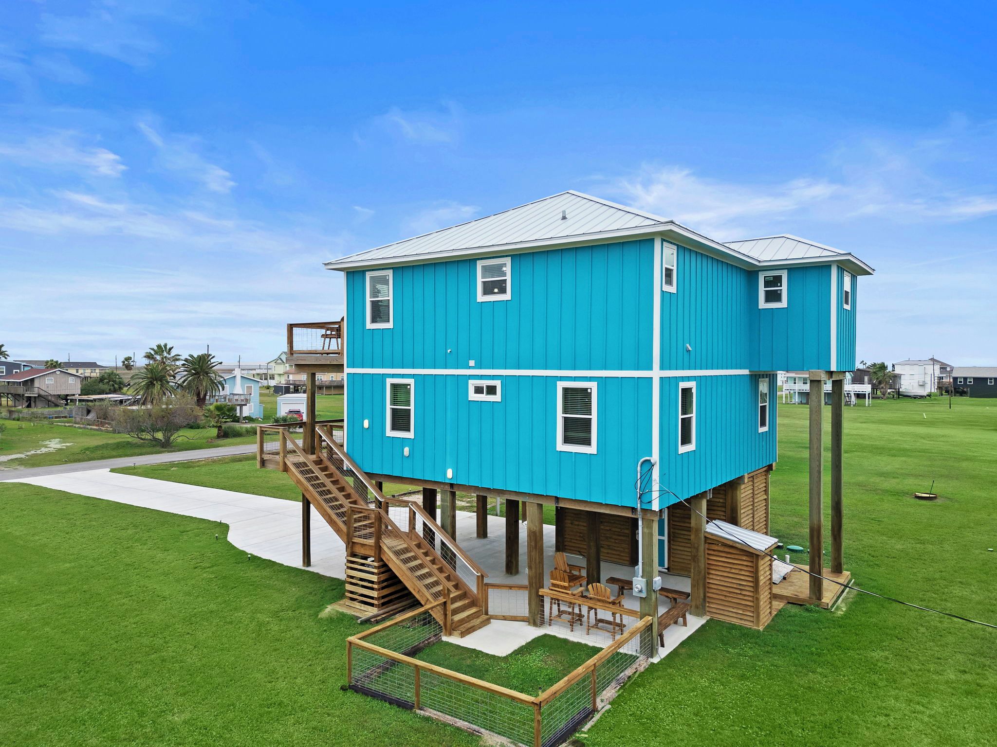 A two-story blue house with a wooden deck and a staircase leading to a balcony.