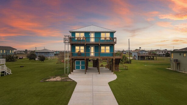 A two-story house with a balcony, a front porch, and a driveway leading to the entrance. - Coral Mountain by Ryson Vacation Rentals (Galveston)