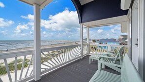 A covered porch with a view of the beach and ocean. - Ocean View by Ryson Vacation Rentals (Galveston)