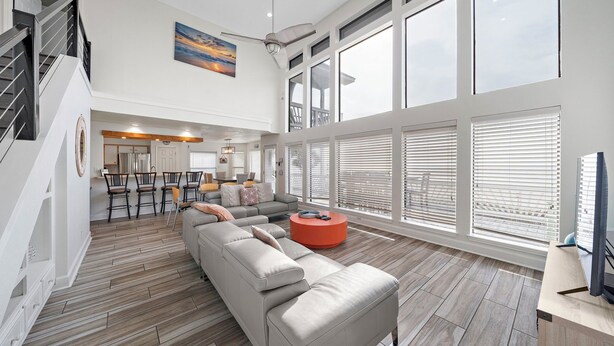 A spacious living area with a large sofa, a round coffee table, and a dining area with chairs. - Ocean View by Ryson Vacation Rentals (Galveston)