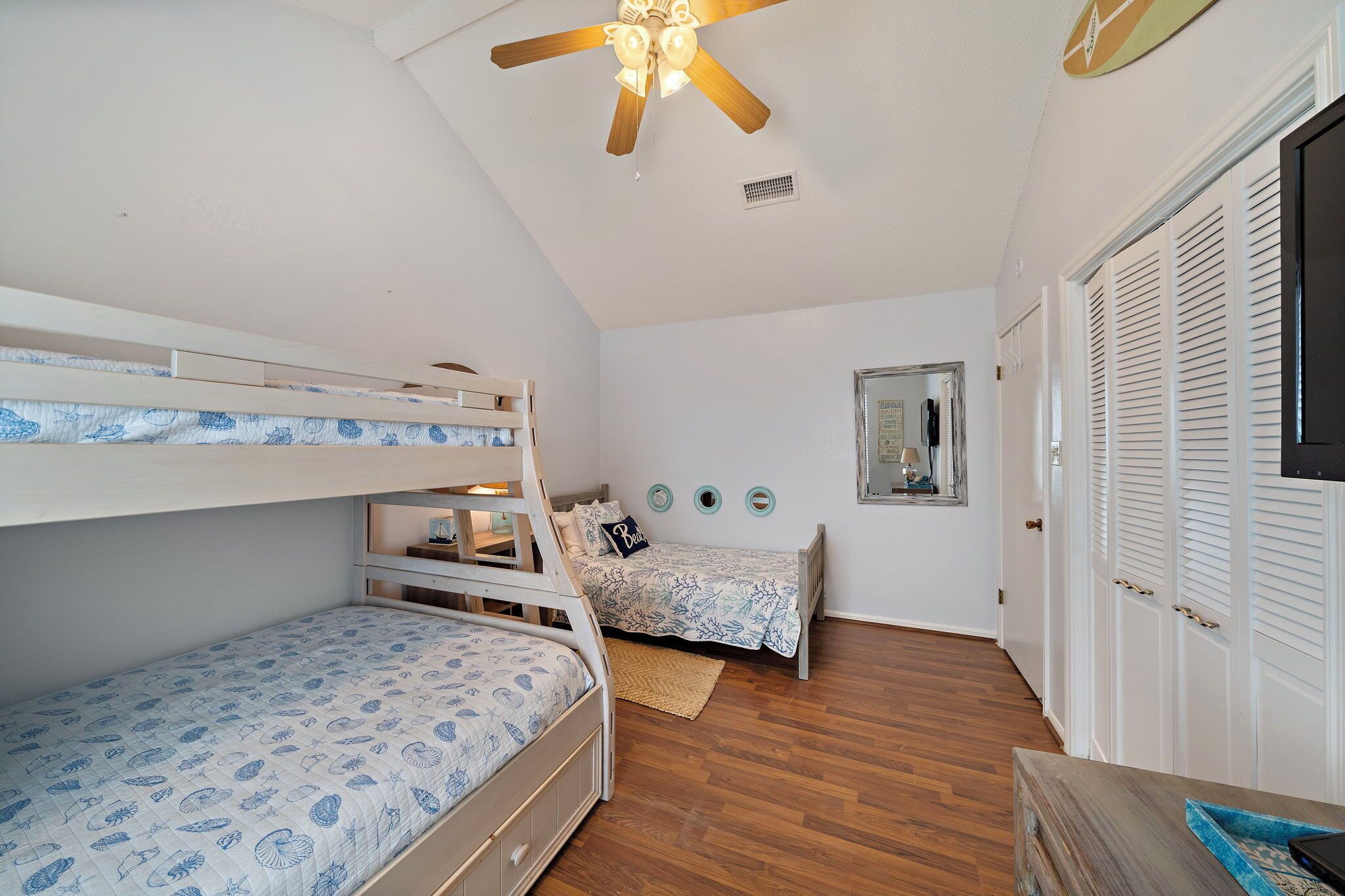 Ein Schlafzimmer mit Etagenbetten, Deckenventilator, Spiegel und Kleiderschrank.