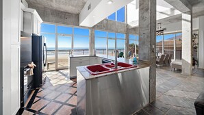 Une cuisine spacieuse dotée d’un grand îlot central, d’un réfrigérateur et offrant une vue sur la plage.