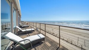 Une terrasse avec des chaises longues donnant sur une plage.