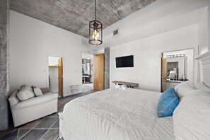 Une chambre à coucher moderne, dotée d’un grand lit, d’un canapé, d’une télévision et d’une coiffeuse avec un miroir.