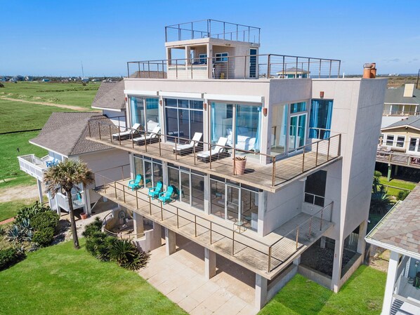 Ein modernes mehrgeschossiges Haus mit Balkon, großen Fenstern und einem Poolbereich.