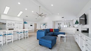 A modern kitchen with white cabinets, a microwave, and a ceiling fan. - The Beach House by Ryson Vacation Rentals (Galveston)