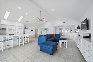 A modern kitchen with white cabinets, a microwave, and a ceiling fan.