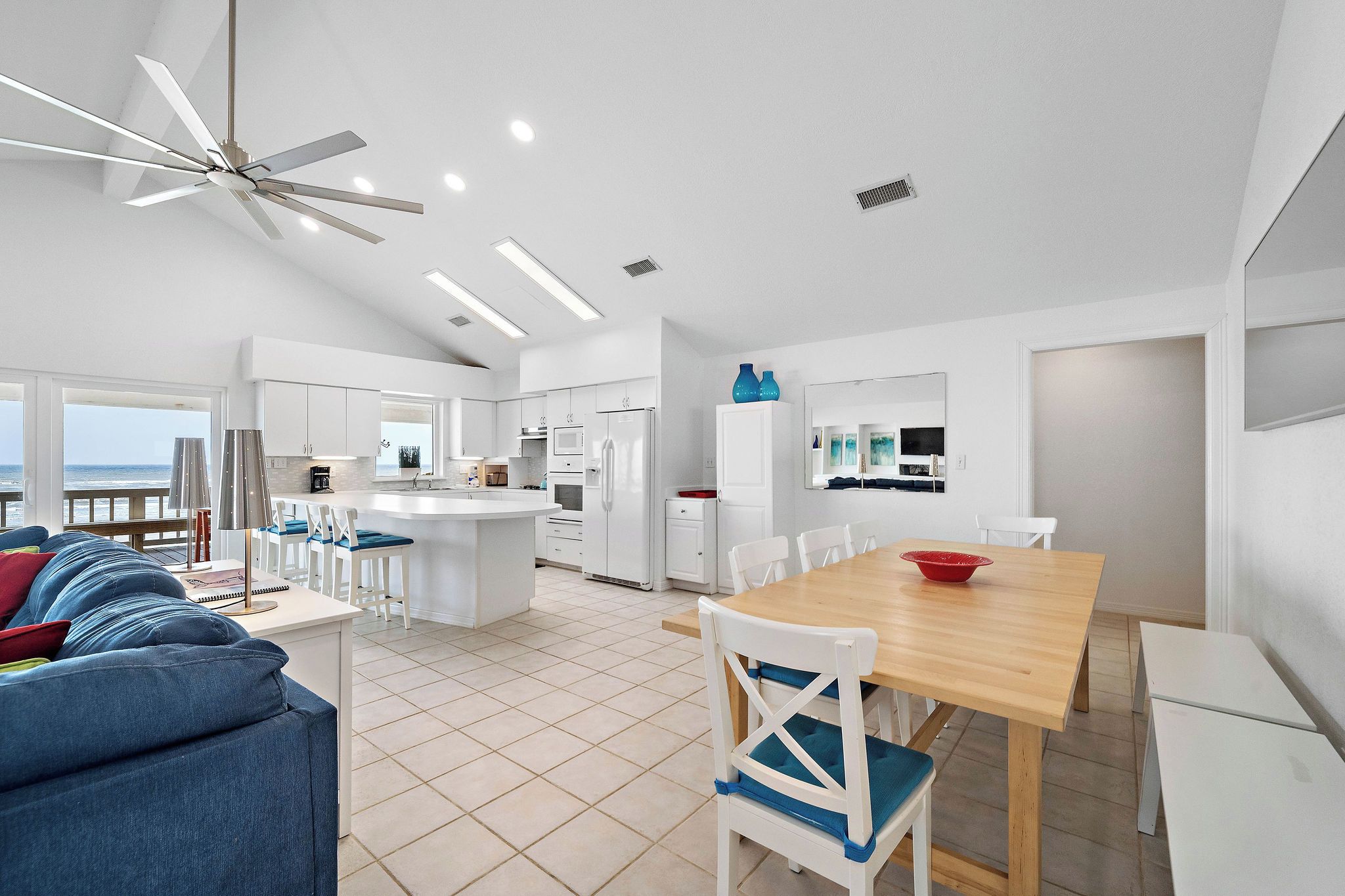 Un espacio habitable amplio con un sofá grande, una mesa de comedor de madera y una cocina al fondo.