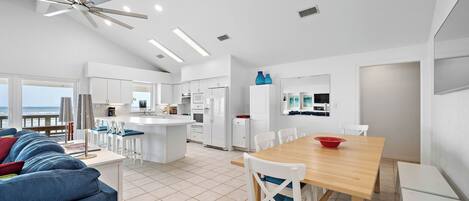 Un espacio habitable amplio con un sofá grande, una mesa de comedor de madera y una cocina al fondo.