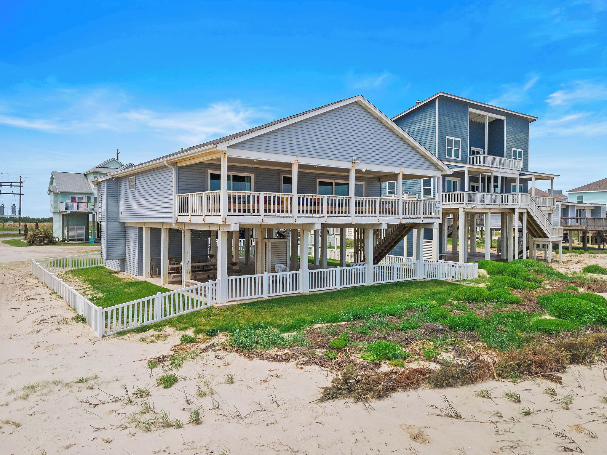 Ein Strandhaus mit mehreren Etagen, Balkonen und einer überdachten Veranda.