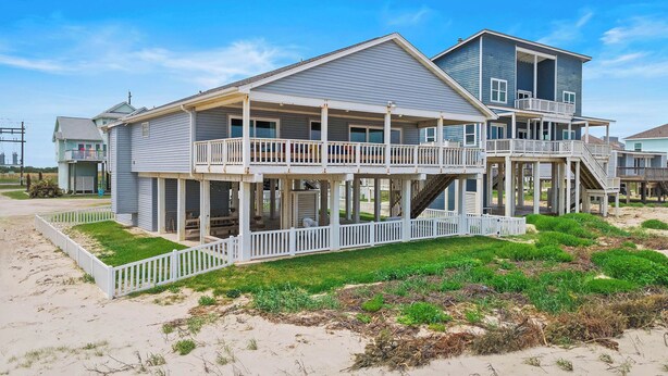 A beachfront house with multiple levels, balconies, and a covered porch area. - The Beach House by Ryson Vacation Rentals (Galveston)