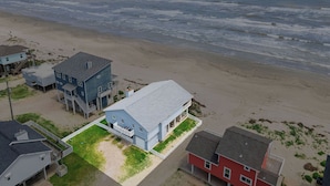 A coastal property with a large house featuring a balcony and a smaller attached structure. - The Beach House by Ryson Vacation Rentals (Galveston)