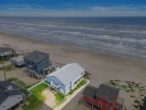 Une propriété située sur la côte, comprenant une grande maison dotée d’un balcon et d’une dépendance plus petite attenante.