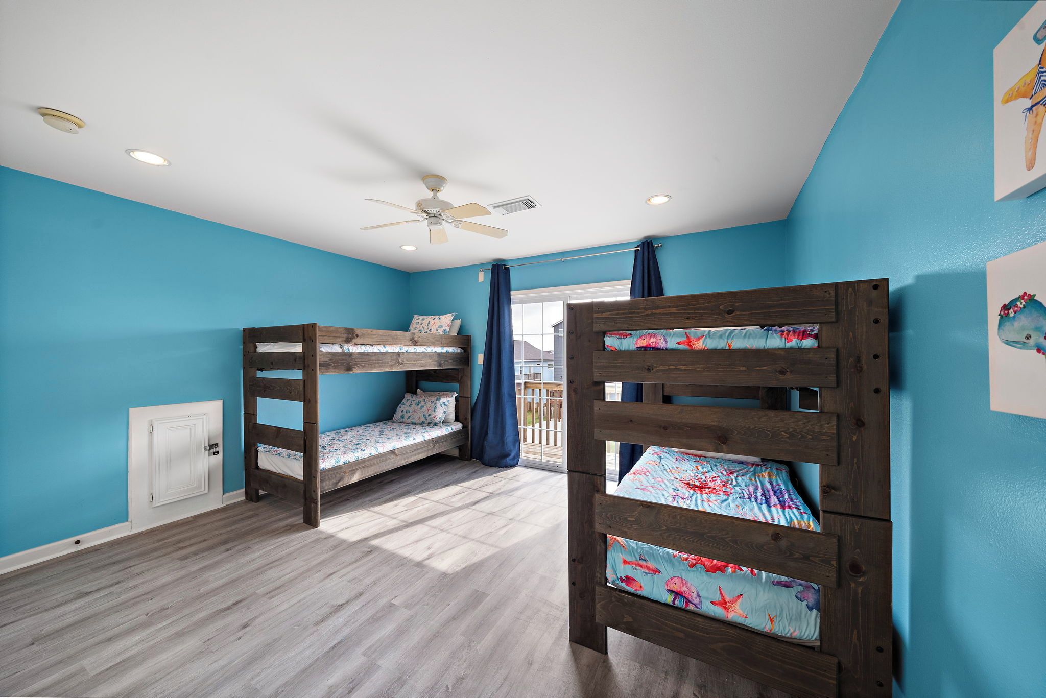 A room with two bunk beds, a ceiling fan, and a window with curtains.