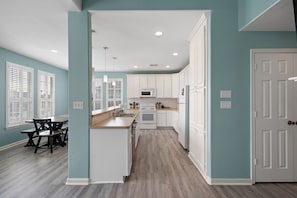 A modern kitchen with white cabinets, a microwave, and a dining area with a table and chairs.