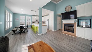 A spacious living area with a dining table, kitchen, and fireplace. - The Krusty Krab by Ryson Vacation Rentals (Galveston)
