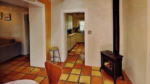Ein Wohnzimmer mit einer Couch, einem Sessel, einem Tisch und einer Küche im Hintergrund.