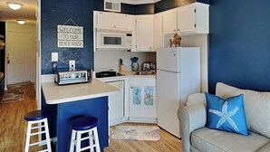 Una cocina compacta con barra, armarios blancos y una pared de acento azul.