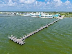 A long pier extending into a body of water with a row of buildings in the background.