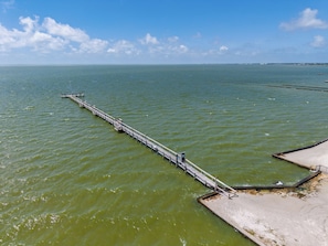 A long pier extending into a body of water with a clear sky above.