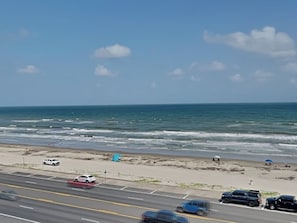 Eine Küstenstraße mit Fahrzeugen, einem Sandstrand und dem Meer.