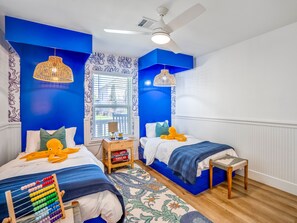A bedroom with two beds, a ceiling fan, and a window with blinds. - Sandy Toes Retreat by Ryson Vacation Rentals (Galveston)