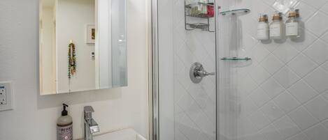 A modern bathroom with a white sink, a mirror, and a glass shower enclosure.