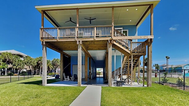 A two-story building with a balcony, a covered outdoor area, and a staircase leading to the upper level. - Play N Hooky by Ryson Vacation Rentals (Galveston)