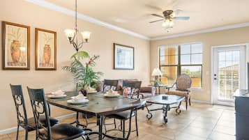 A dining area with a table set for four, surrounded by chairs, a ceiling fan, and a potted plant.