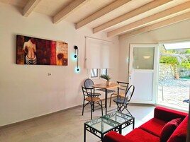 Un comedor con una mesa y sillas, una mesa de centro de vidrio, un sofá rojo y un cuadro en la pared.
