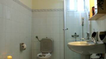 Un baño con inodoro, bidé, lavamanos y cabina de ducha.