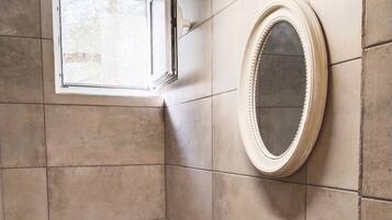 Une salle de bain moderne avec un lavabo noir, un miroir rond et une petite plante en pot.