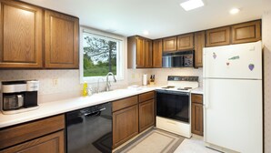 Eine moderne Küche mit Holzschränken, einer Edelstahl-Mikrowelle, einem eingebauten Backofen und einem weißen Kühlschrank.