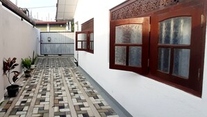 A narrow corridor with patterned tile flooring, a white wall, and a wooden door with glass panels. - Dream villa and homestay madiha Home (Madiha)