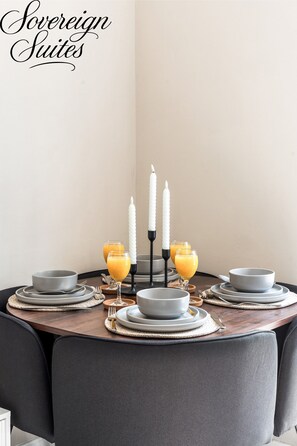 A dining table set with plates, glasses, and candles.