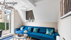A modern living room with a blue sofa, a coffee table, and a large window.