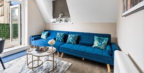 Un salon moderne avec un canapé bleu, une table basse et une grande fenêtre.