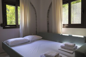 A neatly made bed with white linens, a grey headboard, and two windows with curtains. - Rea Villa, Vourvourou (Vourvourou)
