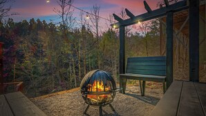 An outdoor seating area with a fire pit, wooden benches, and a pergola.