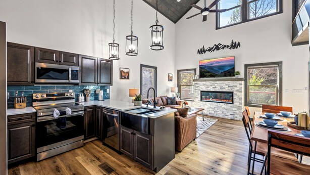 A modern kitchen with a central island, built-in appliances, and a stone fireplace.