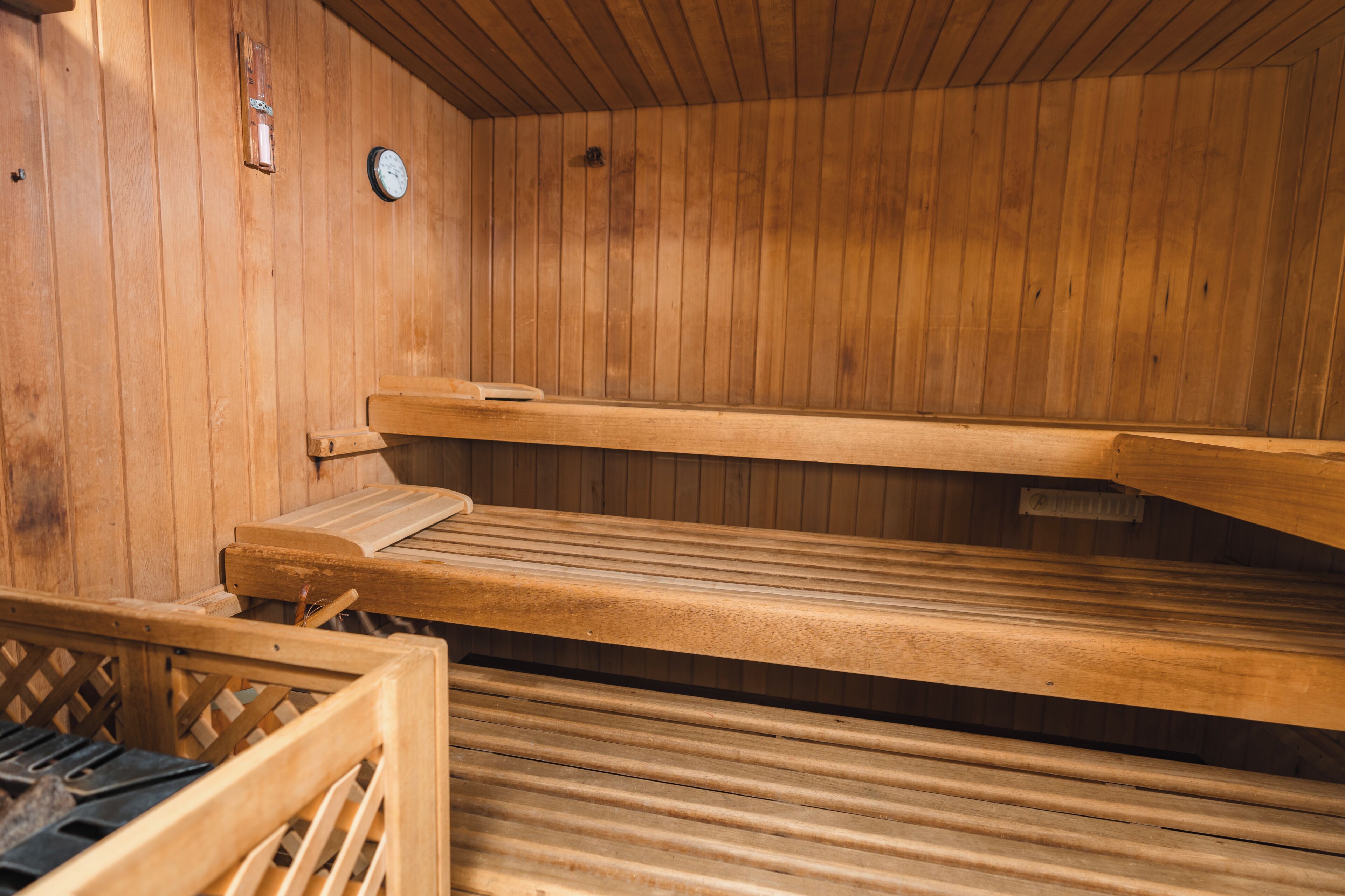A sauna with wooden benches and a clock on the wall.