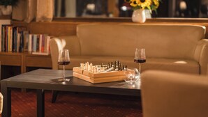 A chessboard on a table with two glasses of red wine, a sofa, and a bookshelf in the background. - Smart Hotel Firn (Senales)
