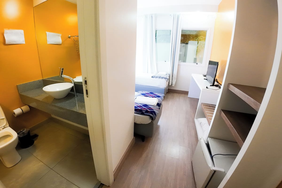 Ein kleines Hotelzimmer mit Bad, Bett und Schreibtisch.